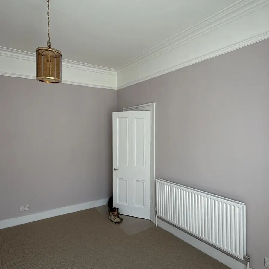 Bedroom painted lilac with white cornice and panelled door