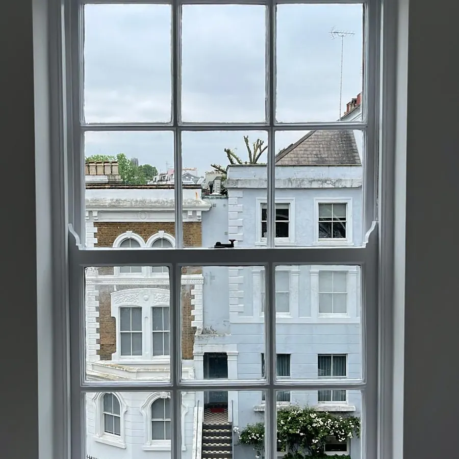 Sash window painted white, looking out over London terraces