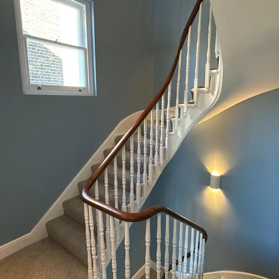 Staircase with blue-grey walls, white spindles and a mahogany handrail