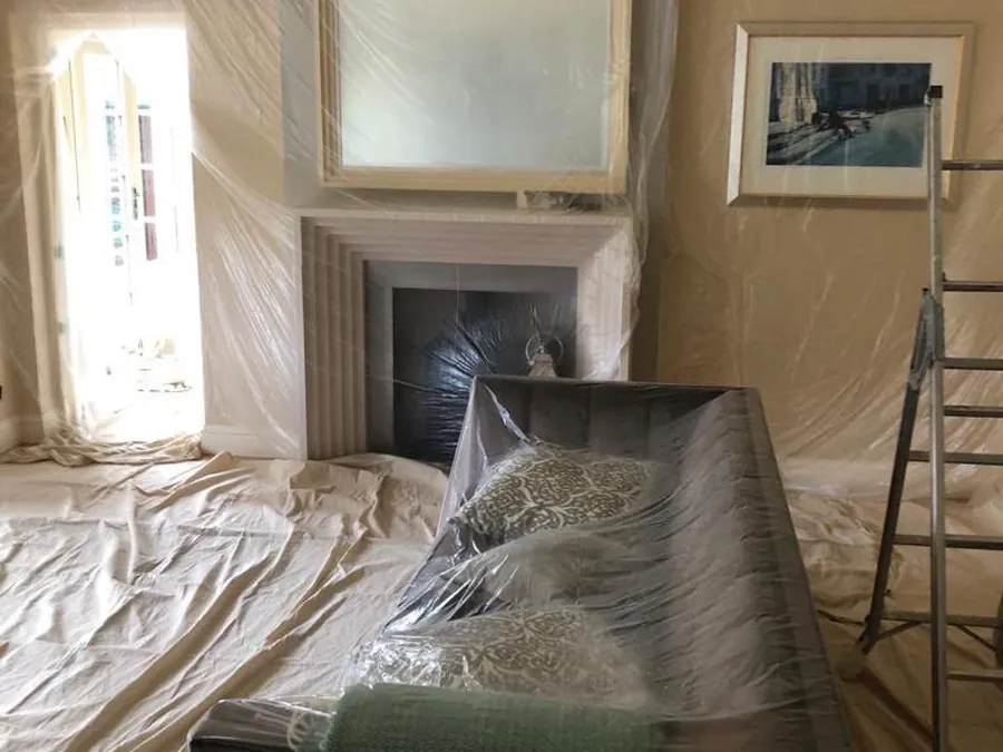 Living room with furniture sheeted, floors covered and the fireplace masked before work starts