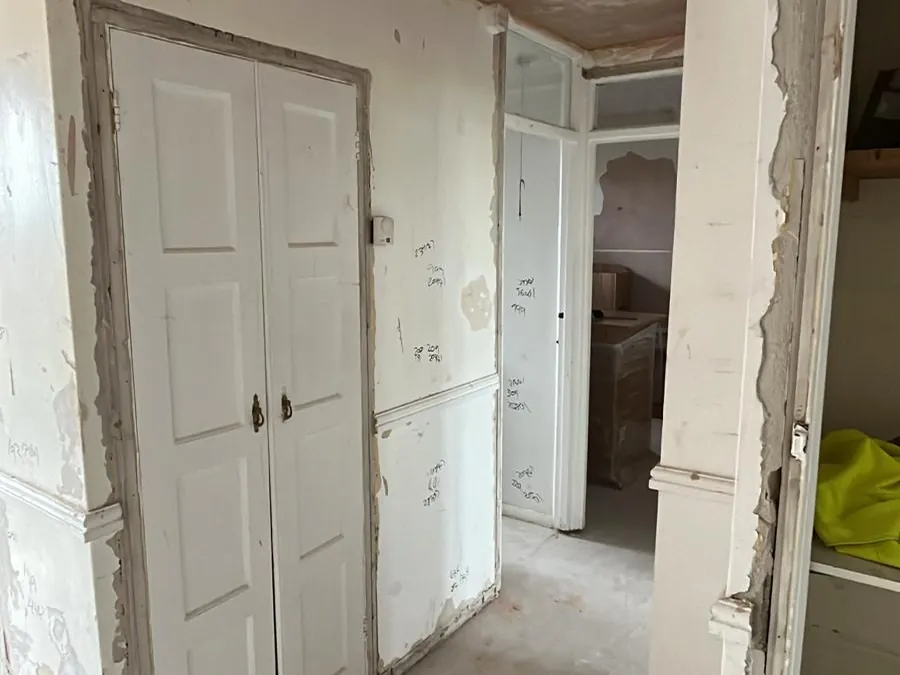 Hallway with old paint and paper stripped back around the doors