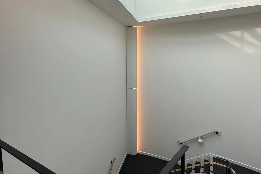 Stairwell painted white, with dark stair covering and handrail